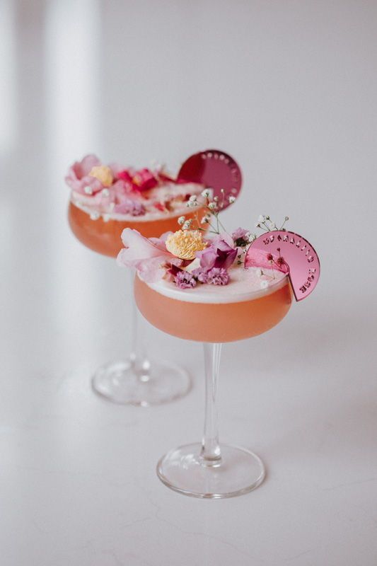 Two fancy looking rose drinks on a white background.